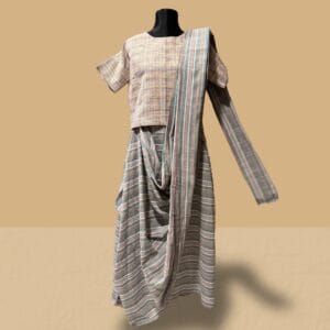 This ensemble by Taan fuses heritage with modernity, featuring a khadi drop-shoulder crop top for a structured yet breathable feel, paired with an adjustable saree-inspired skirt adorned with multicolor stripes that drape fluidly while offering a contemporary, versatile fit. The vibrant striped pattern adds depth and movement, making it a statement piece that blends tradition with innovation. Care: Wash gently with lukewarm water or opt for dry cleaning to maintain the fabric’s texture and vibrancy.